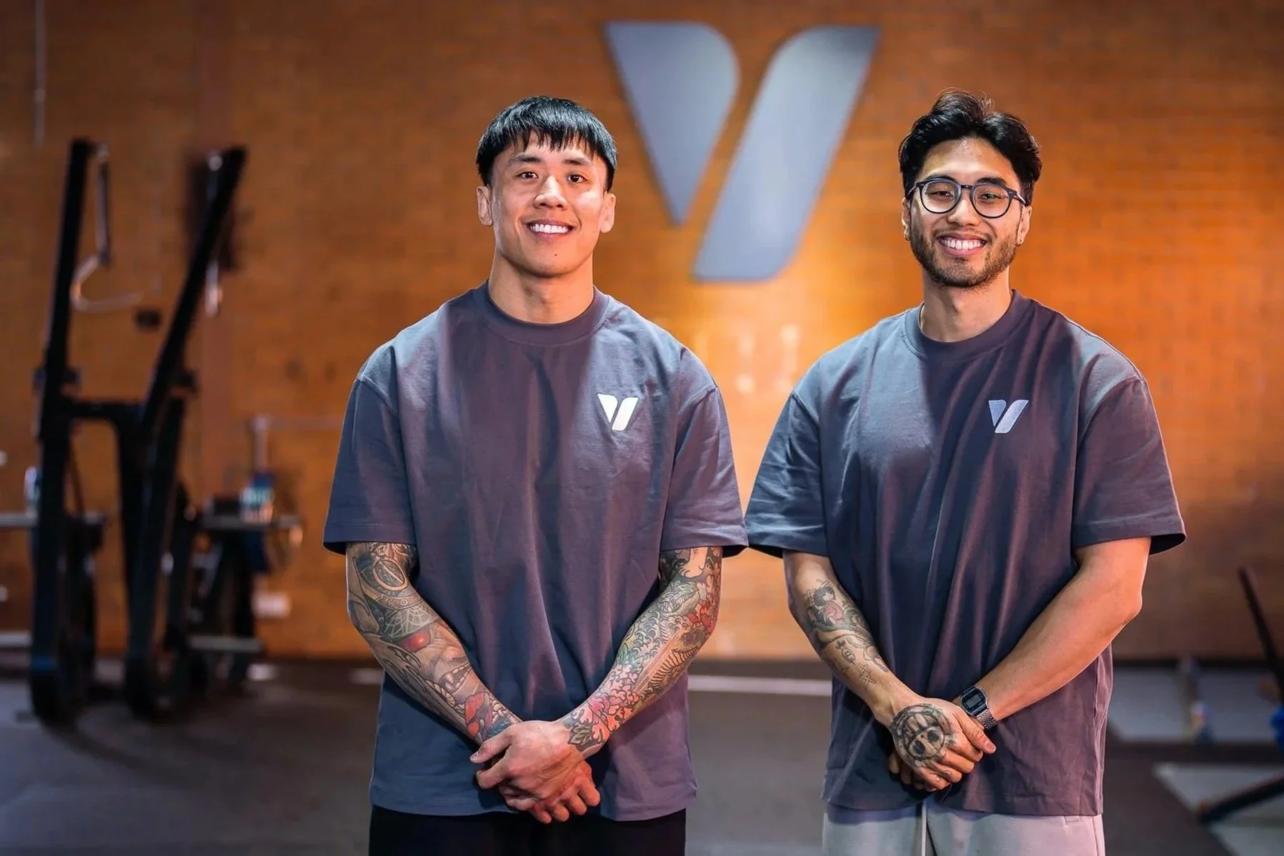 Founders Matt and Khoi standing in front of the Vigor HQ brick wall