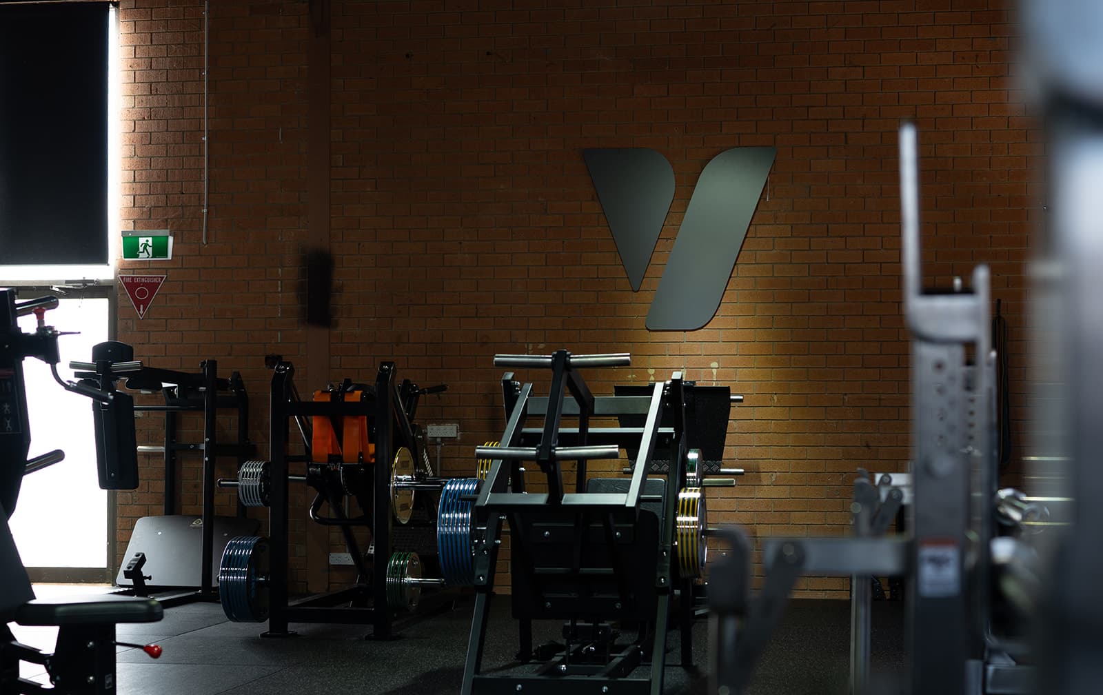 Vigor HQ gym equipment in front of the brick wall logo