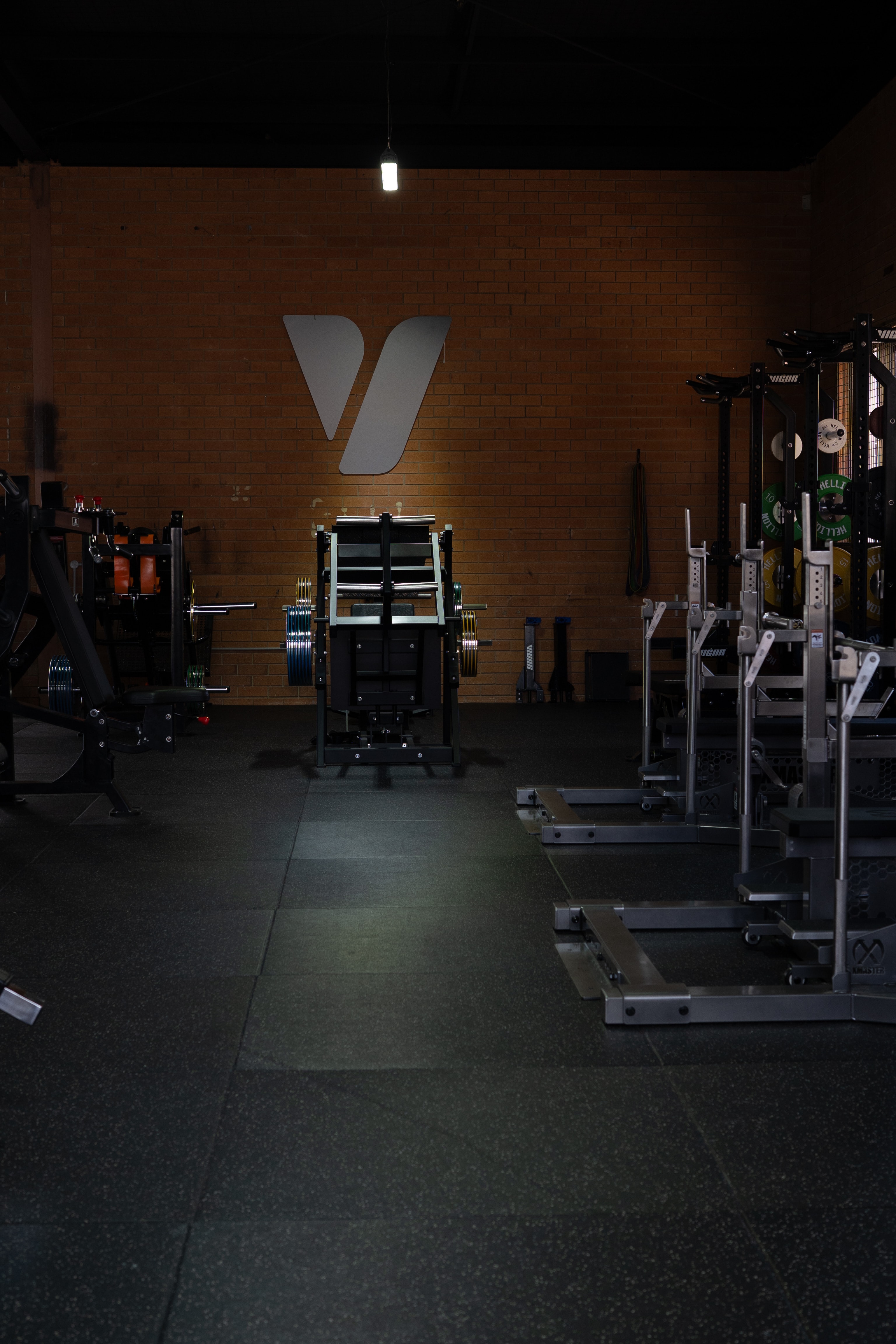 Long view of the Vigor HQ gym floor with the logo mounted on the brick wall